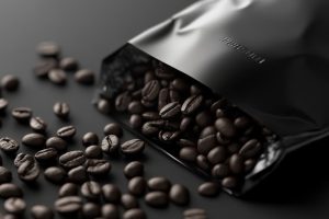 Dark roast coffee beans spilling out of a sleek black bag.